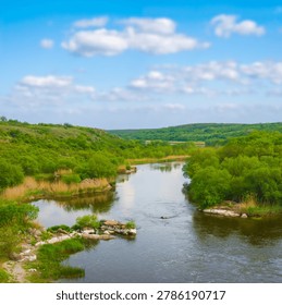 small river flow through green canyon under a blue cloudy sky