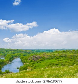 small river flow through green canyon under a blue cloudy sky