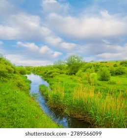 small river flow through green canyon under a blue cloudy sky