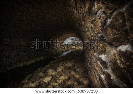 Small river flowing under the old brick bridge 