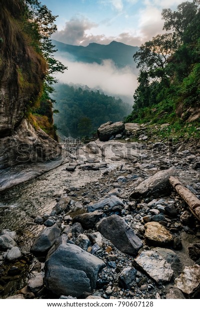 Small river in valley and donkeys crossing metal\
suspension bridge in background in Nepal, Himalayas, Manaslu\
circuit trek 2017