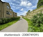 Small road, running past housing, and a large stone wall, on an early spring day in, Briggate, Shipley, UK