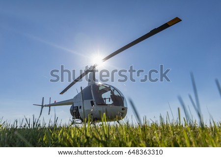 Small Robinson R22 light utility helicopter parked on grass airport. One of the world's most popular light helicopters with twin blades and a single engine [[stock_photo]] © 
