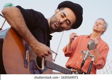 Small Rock Pop Band Playing On A Rooftop In Spring Live Festival. Man In Adult Age Performing On Summer Season. Music Live Concerts Concept. Intimate Concert Abut To Start With Hipster Rock Music.