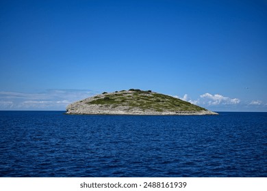 Small rocky island emerging from the deep blue sea on sunny summer day. - Powered by Shutterstock