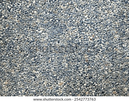 Small round stones texture background. Rough surface of small pebble stone. Abstract background paving consisting of small pebbles embedded in cement