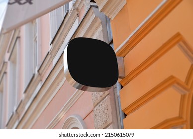 Small Rounded Black Sign On The Facade Of The Building In The Main Street. Blank For Company Logo Promotion