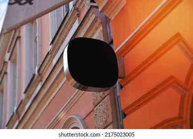 Small Rounded Black Sign On The Facade Of The Building In The Main Street. Blank For Company Logo Promotion