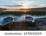 Small rowboats lay on the lake coast under sunset sky, Karelian landscape photo 