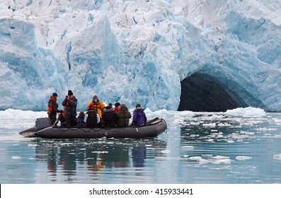 A small rubber dingy in front of a big glacier wall.