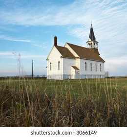 Small rural church in field with chipped wood siding.