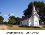 A small rural church in Texas.  There is a cemetary and a large oak tree behind the church.