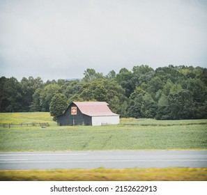 A Small Rural House In A Big Green Field With Trees