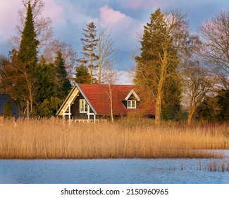 A Small Rural House Surrounded By Trees Near The River