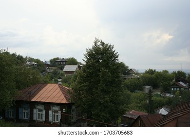 small rural houses on a hill among green trees in summer against a blue sky