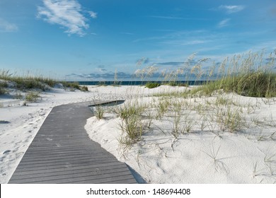 Small rustic boardwalk footpath through snow white sand dunes at a pristine Florida beach.