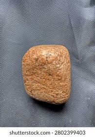 Small rustic granite stone isolated on textured dark background