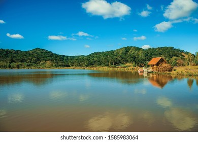 Small rustic shack reflected on the lake of crystal clear water and hills covered by grove near Cambara do Sul. A small country town in southern Brazil with amazing natural tourist attractions.