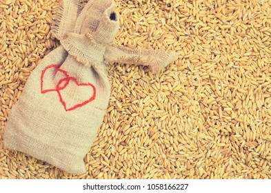 Small sacks of sacking with the image of two hearts on scattered grains of cereals.