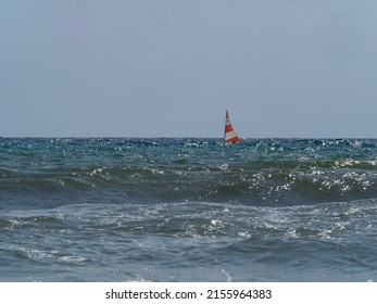 Small Sailing Boat Overhung By The Waves In The Rough Sea On A Sunny Summer Day
