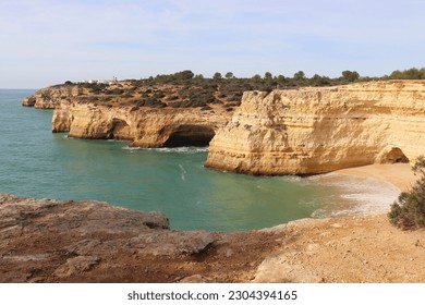 Small sandy beach and limestone cliffs around water in the Atlantic Ocean on a sunny winter day in southern Portugal on the Seven Hanging Valleys Trail.