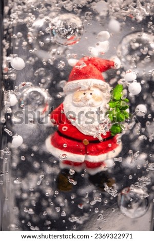 A small Santa Claus incorporated in transparent candle wax and a small green Christmas tree