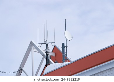 Small satellite dish antenna นn rooftop behind building dark cloudy sky is background. Antenna communication technology. Telecommunication link 5G Digital Transformation connect to data Internet.
