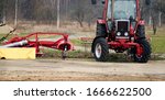 Small scale farming with tractor and plow in field.