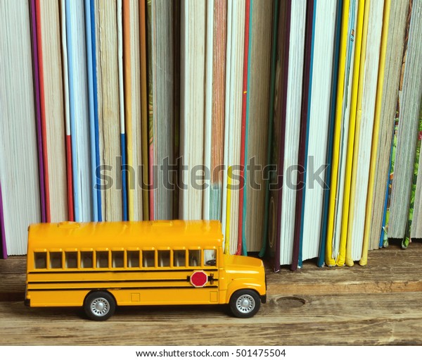 small school bus on a\
shelf with books\
