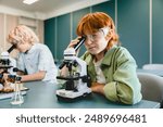 Small schoolkids pupils students classmates using working with microscope at biology chemistry lesson class at school lab. Science lesson concept