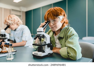 Small schoolkids pupils students classmates using working with microscope at biology chemistry lesson class at school lab. Science lesson concept - Powered by Shutterstock