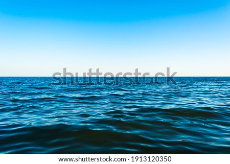 Small sea waves against the blue sky and white horizon