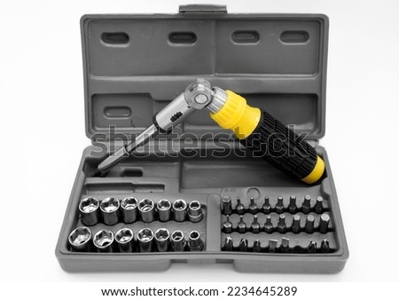 small set of tools with a screwdriver with removable bits and a ratchet wrench with sockets and an adjustable wrench on a white background. car service and construction repair concept. close-up
