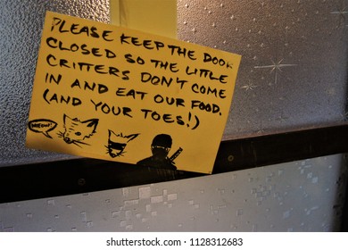 Small sheet of paper warning to keep the door closed to protect the little critters don't come in and eat food was mounted on the glass wall.