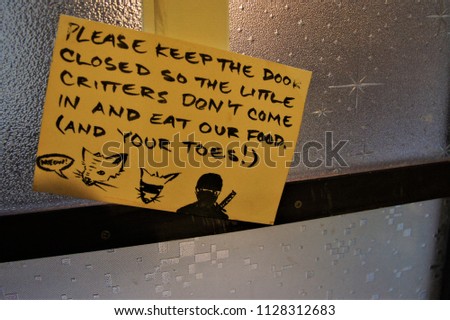 Small sheet of paper warning to keep the door closed to protect the little critters don't come in and eat food was mounted on the glass wall.