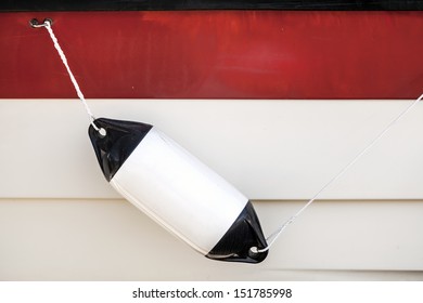 Small ship bump element hanging above white and red yacht hull