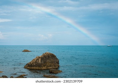 A small ship under a rainbow on the sea horizon. Background