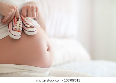 Small shoes for the unborn baby in the belly of pregnant woman