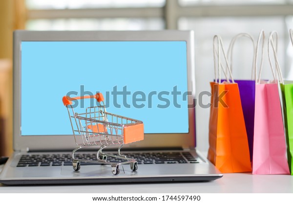 Small shopping cars on laptop and \
bag many colors for shopping online with home background,technology\
business online concept.during the Covid19 virus\
outbreak