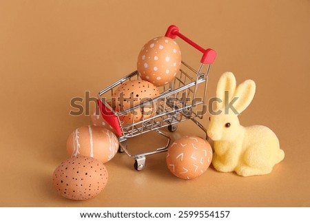 Small shopping cart with Easter eggs and bunny figurine on beige background
