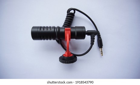 A Small Shotgun Mic With A Jack Cable And White Background