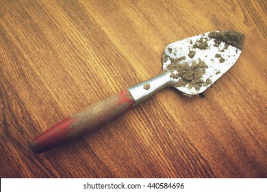 A Small Shovel On A Wooden Background