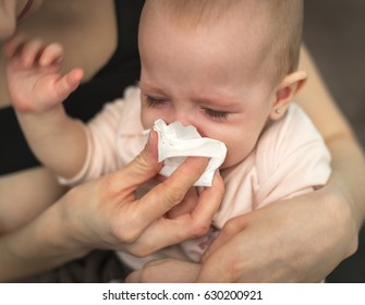 A Small, Sick, Crying Child, Whom The Mother Wipes With A Paper Towel 