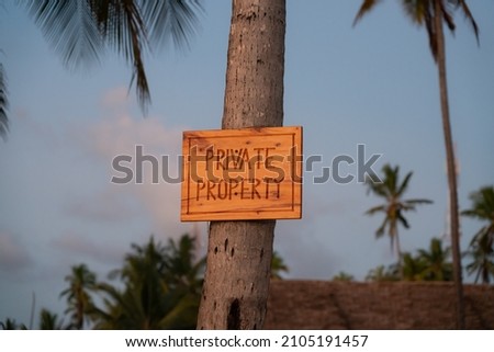 Small sign on the beach marking the private proberty area. Sign post for showing tourists where the private beach starts. Property sign in Zanzibar. Nice colors from the sun.