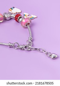 Small Silver Charm Bracelet With Many Charms On Purple Background. Creating Jewelry. Children's Bracelet. Close-up Closure