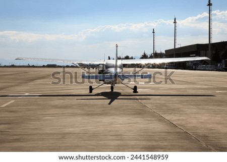 Small single propeller plane parked at the airport on runway.
