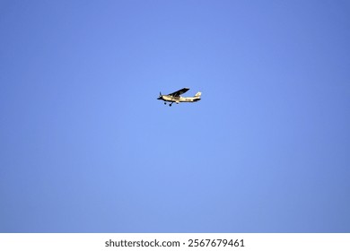 A small single-engine aircraft flying through a clear blue sky, highlighting the simplicity and freedom of aviation.
