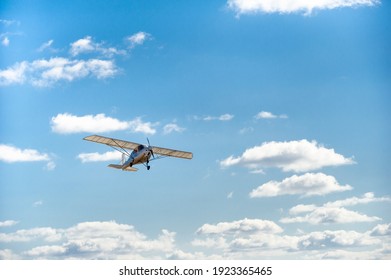 A Small Single-engine Plane Flying Overhead Against The Blue Sky.