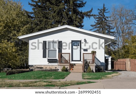 Small, single-story, white house with flat roof and blacks accents.