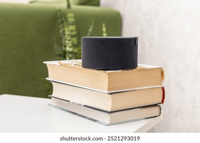 Small smart speaker on stack books. Smart learning assistant